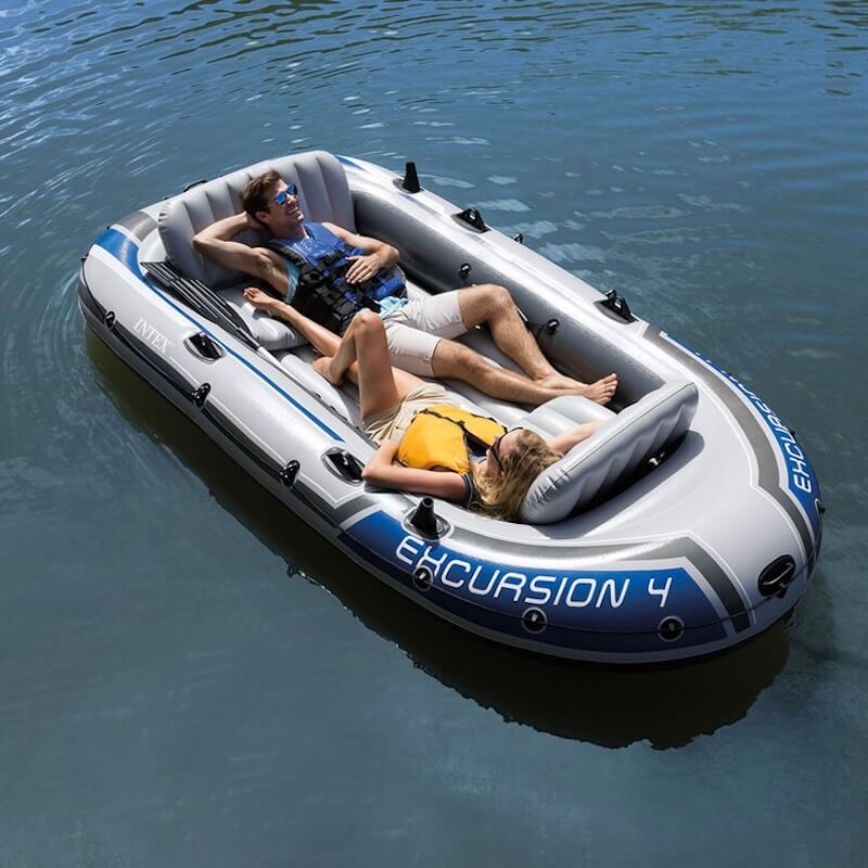 Two people relaxing in an inflatable boat labeled 'Excursion 4' on calm water.